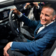 A photo of Herbert Diess sat at the wheel of a car.